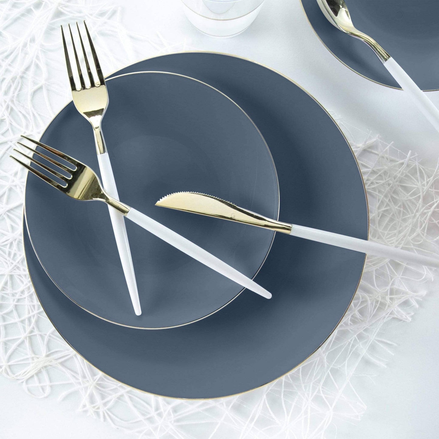 Slate Blue plates with gold cutlery on a white textured surface