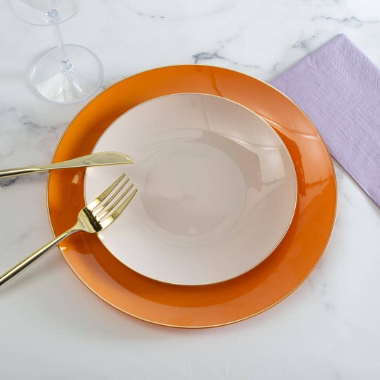 Orange plate with a linen plate, gold fork, and knife on a marble surface.