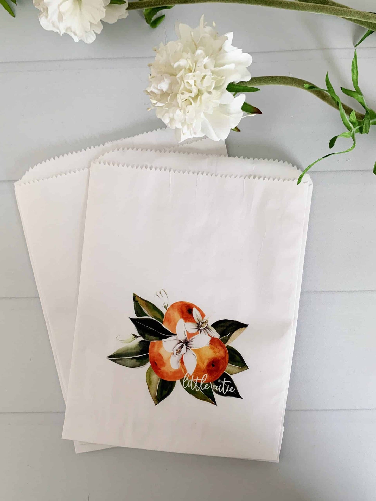 Image of 12 Little Cutie Citrus Treat Bags, each with a cluster of clementine cuties and "little cutie" on the fruit, perfect for a baby shower or candy bar display.