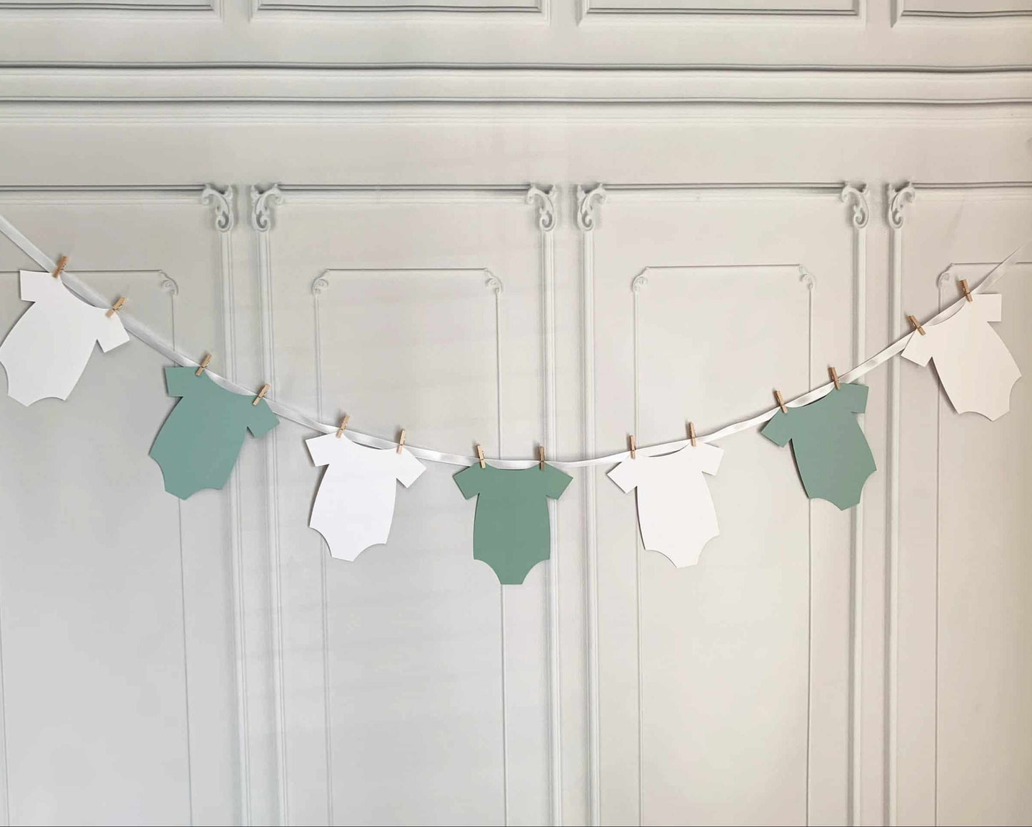 A sage baby shower onesie banner for the Little Cutie on the way! This adorable onesie-shaped banner includes white ribbon for you to hang up the onesies with the clothespins included. Perfect for a greenery or botanical baby shower.