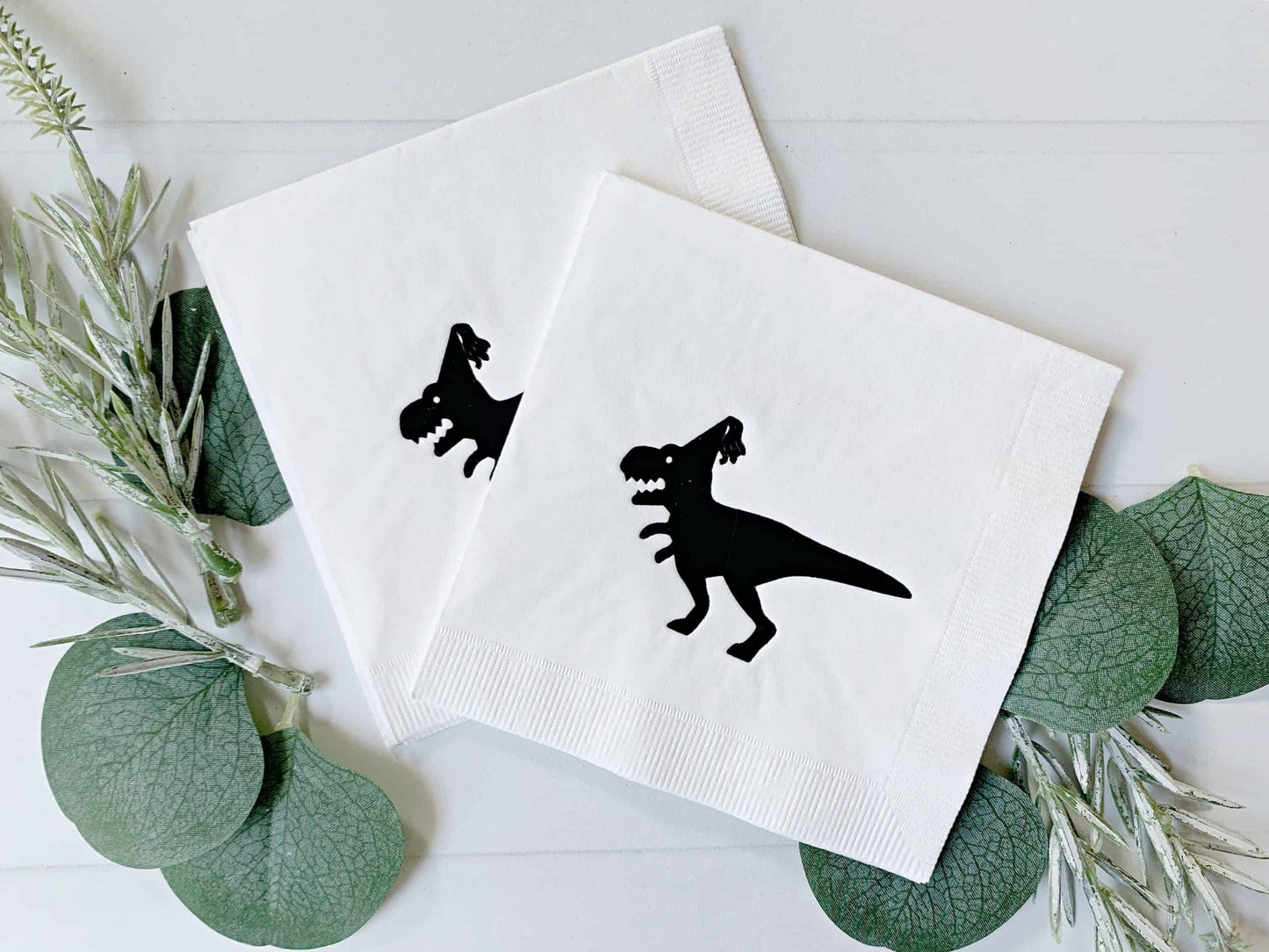 Celebrate your next dinosaur-themed party with these fun Black on White Dinosaur Drink Napkins from EnFete! These playful napkins are perfect for both adults and kids' birthdays, New Year's Eve, or any other special occasion that calls for a prehistoric touch. Featuring an EnFete original design of a dinosaur with a party hat, these napkins are sure to be a hit with your guests.
