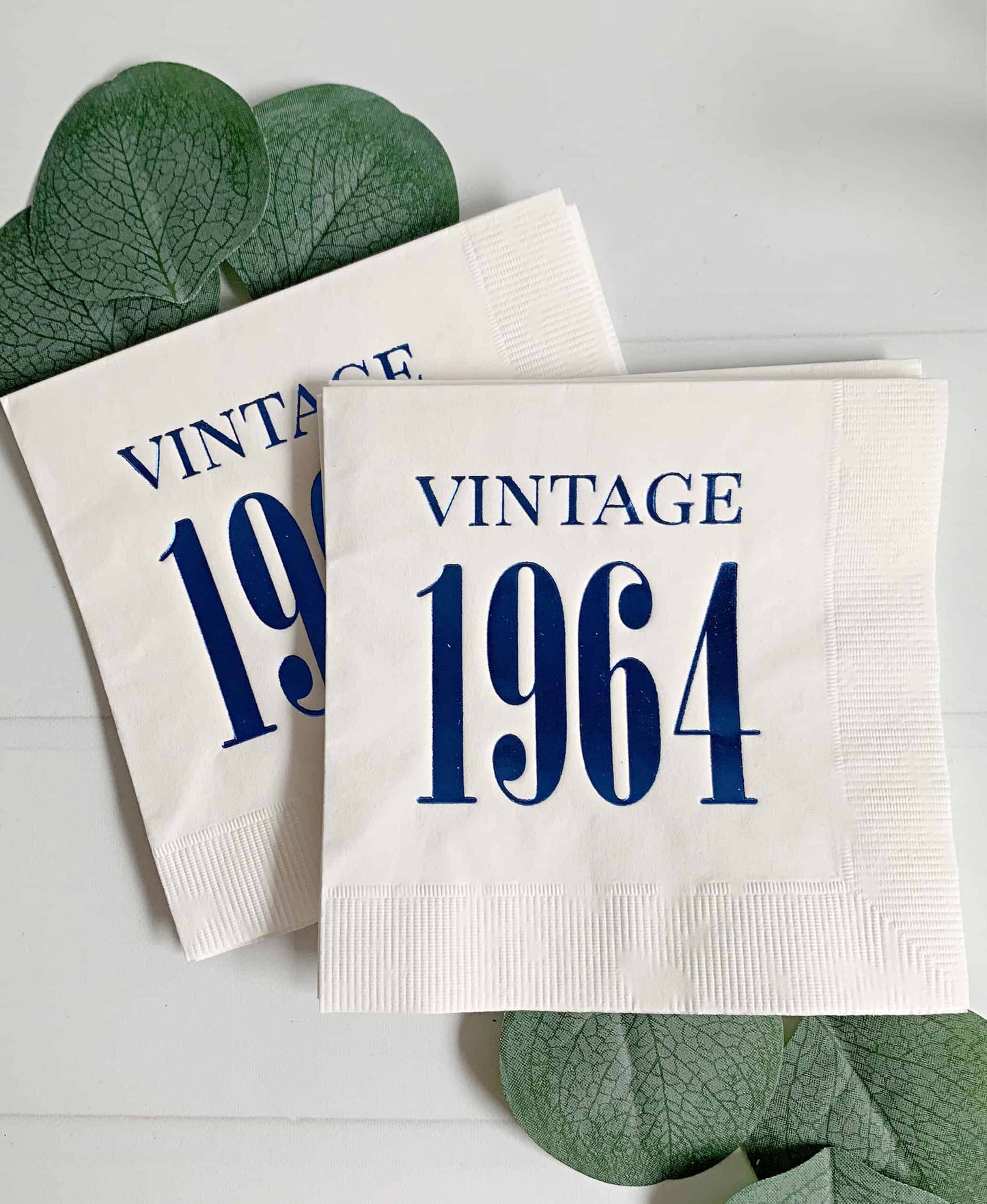 Elevate your celebration with a touch of nostalgia using our Vintage 1964 white with blue foil cocktail napkins. These meticulously crafted napkins pay tribute to the timeless charm of 1964