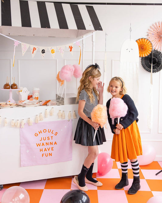 Two children at a Halloween-themed party with cotton candy and decorations.