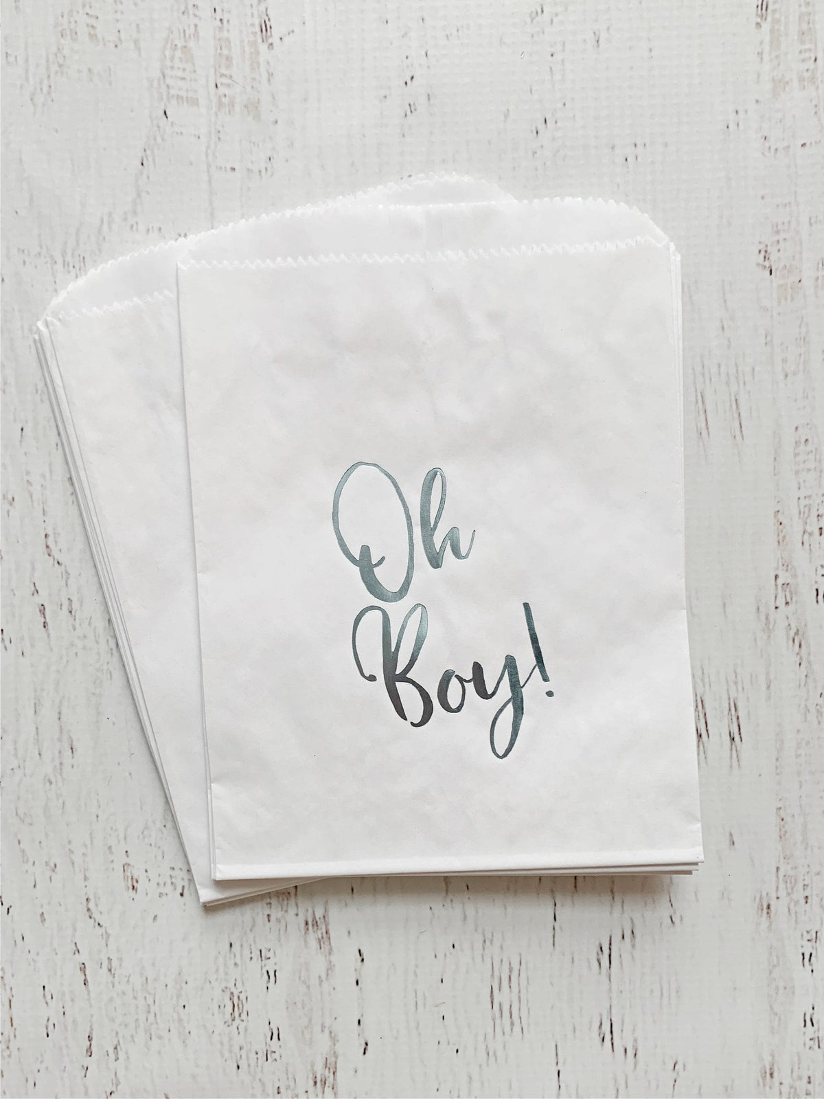 White paper treat bag with 'Oh Boy!' ice blue foil text on a light wooden surface