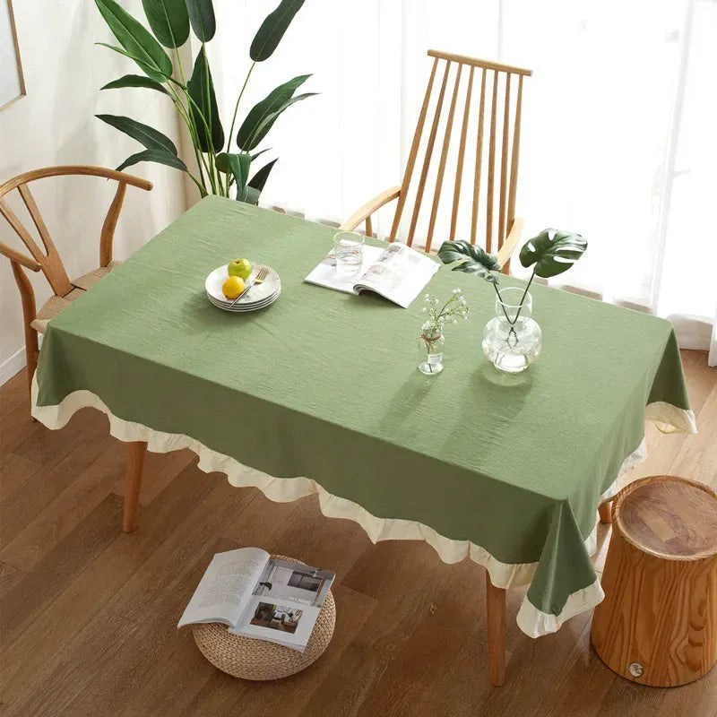 Green tablecloth on a wooden table with decor items in a room.