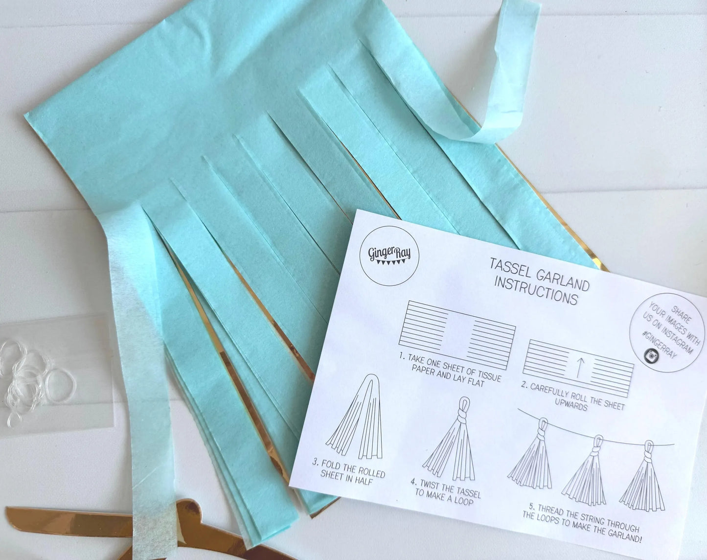 Turquoise tassel garland with instructions on a white surface