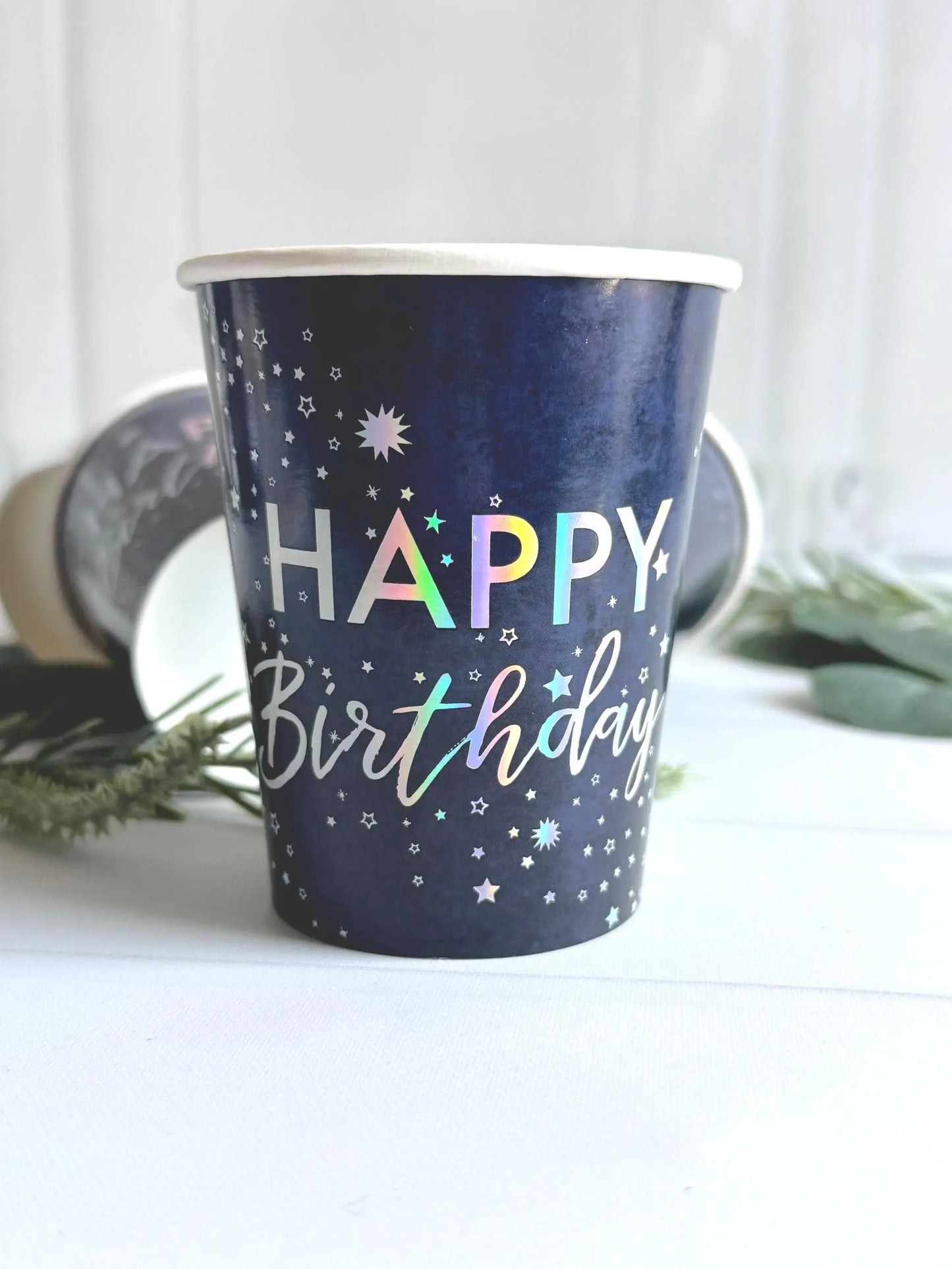 Navy blue paper cup with 'Happy Birthday' text in sparkly silver with a space theme appearance