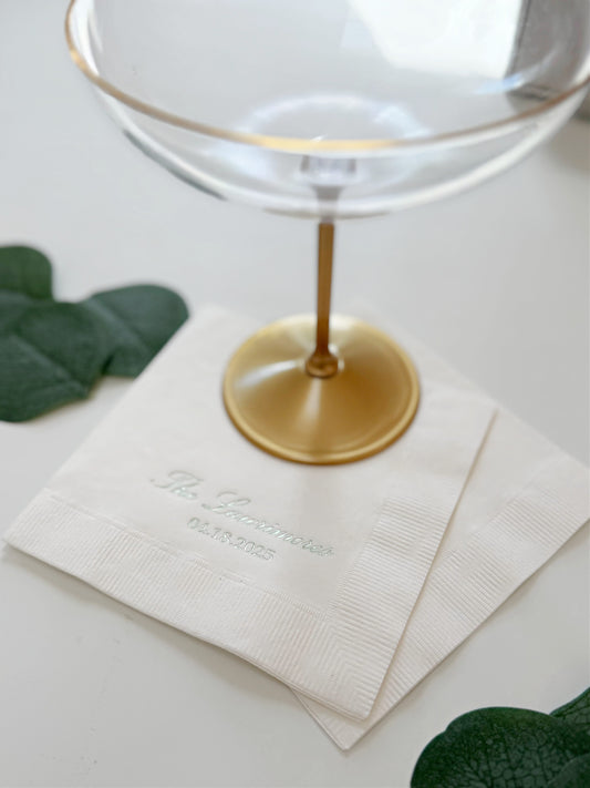 A close-up of a white paper wedding napkins with elegant sage green script with personalization of 'The Garnitures' and the date '09.29.