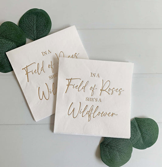 "In a field of Roses She's a Wildflower" in gold foil on white cocktail napkins - the perfect accent for your baby shower. A fun baby shower theme for spring and summer babies.