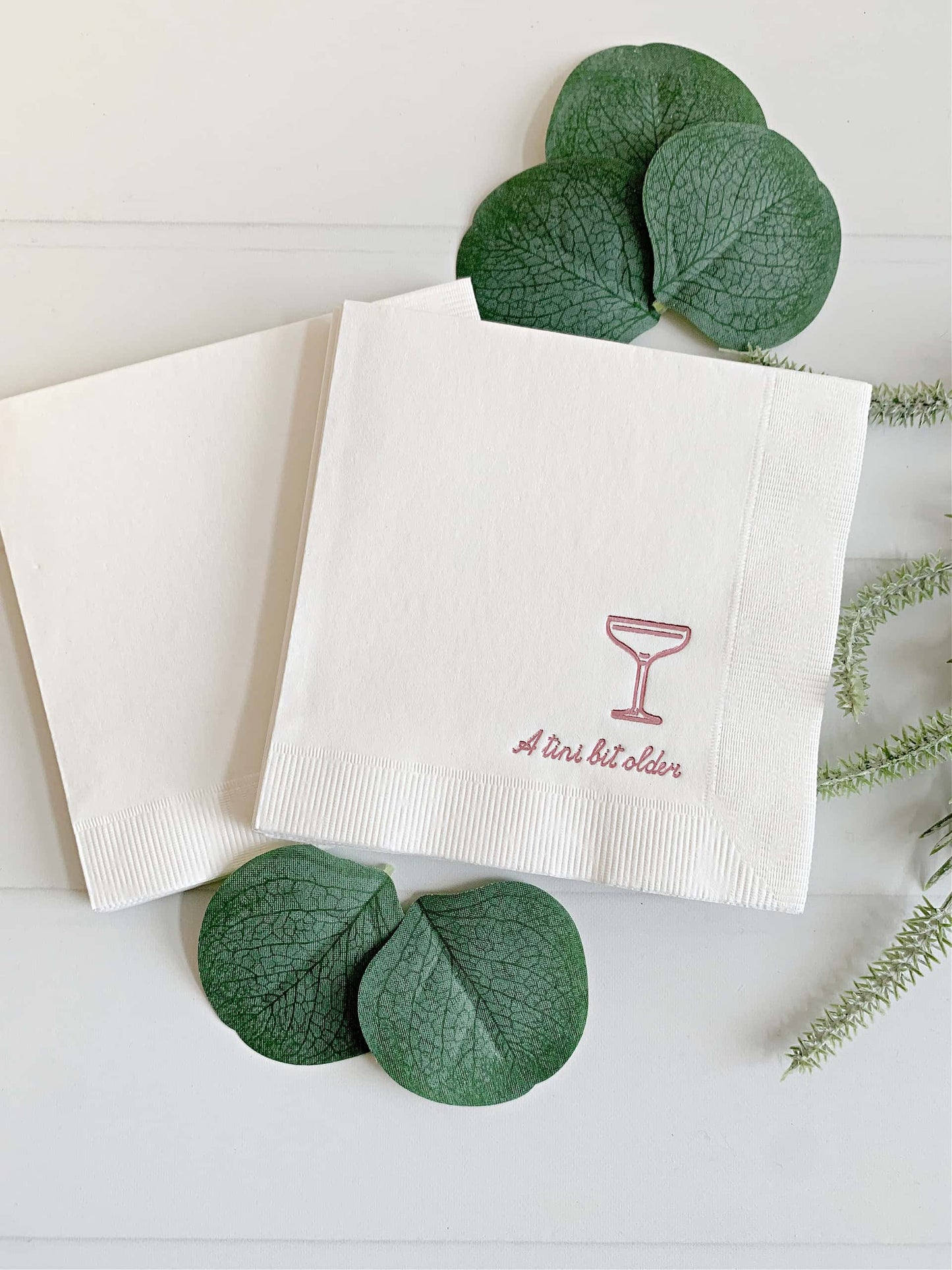 Elevate your birthday celebrations with EnFete's Pink on White "Just a Tini Bit Older" Coup Glass Cocktail Napkins! Designed to bring sophistication and a touch of playful charm to your party