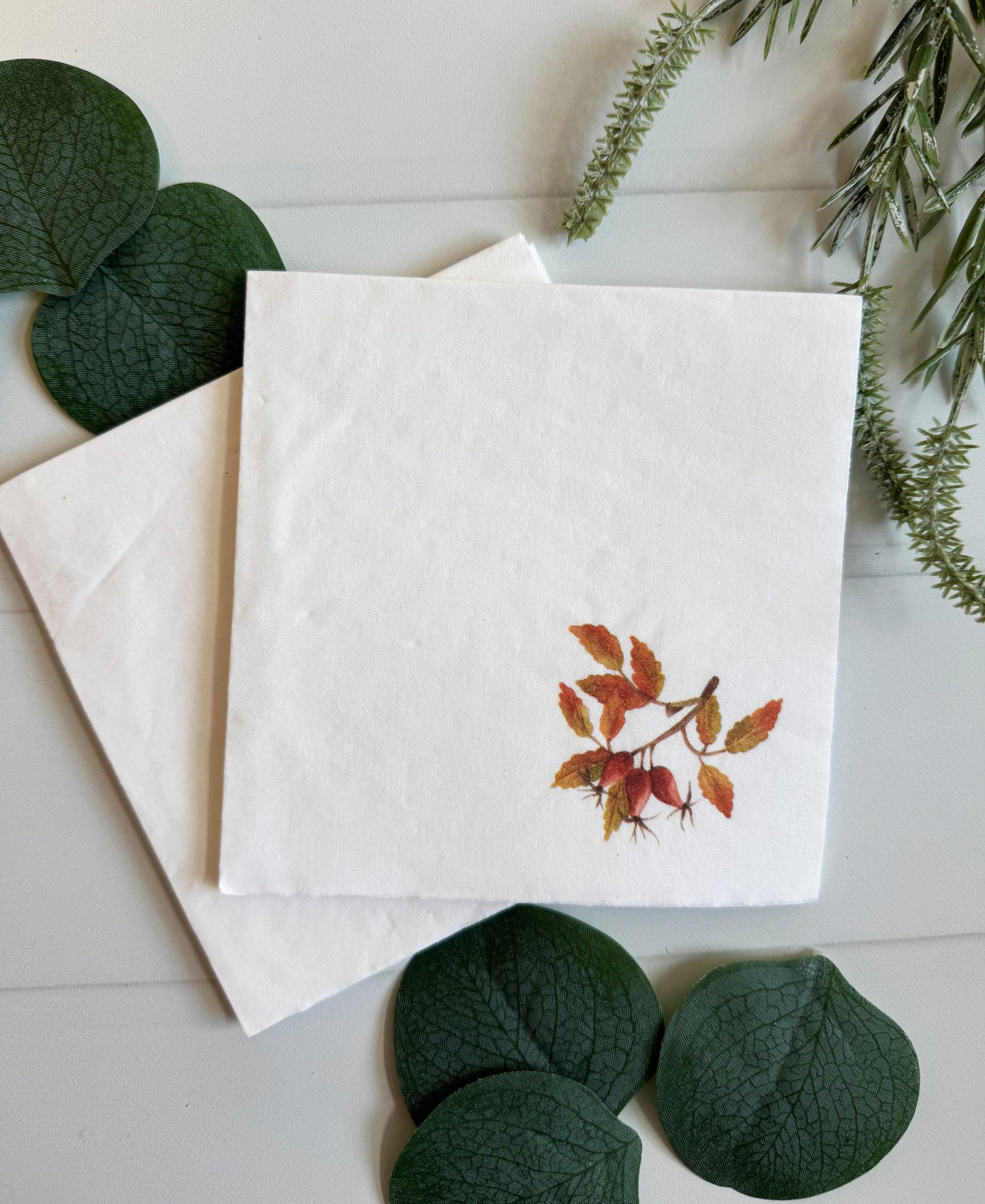 Amber, Red, Orange and a hint of Olive green full color watercolor leaves on a white cocktail napkin.