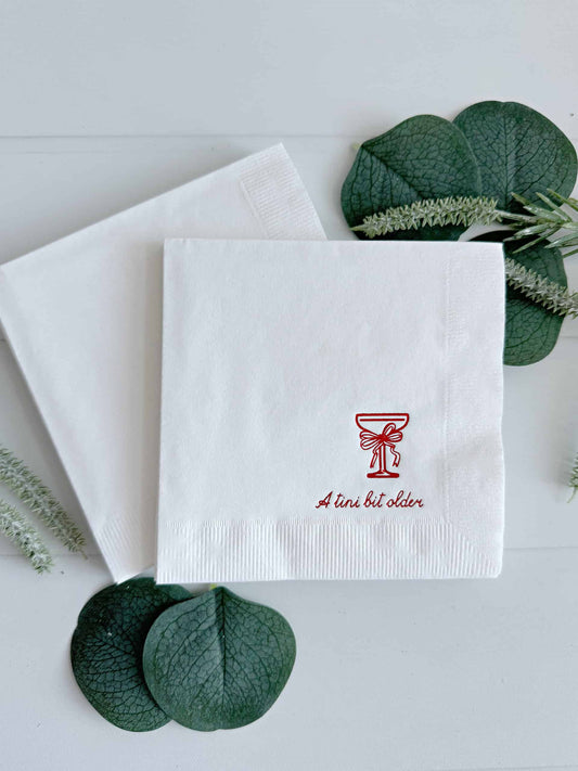 levate your birthday celebrations with EnFete's Cocktail Napkins with Red Foil "Just a tini bit old" Coup Glass and Red Bow Birthday Cocktail Napkins. Perfect for a holiday or December birthday!