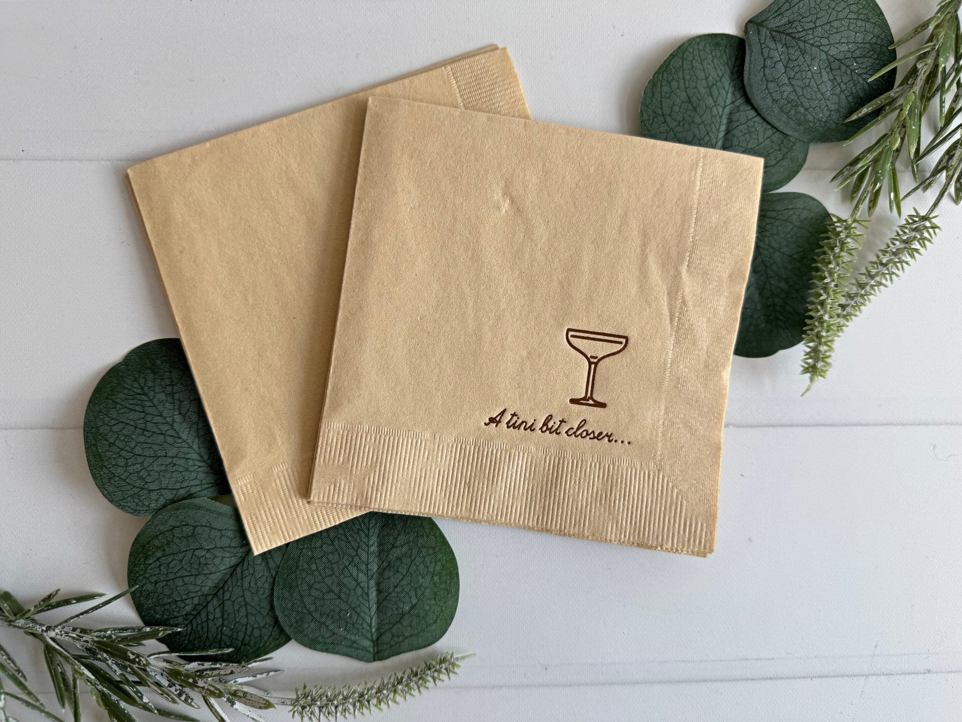 Elevate your prewedding celebrations with EnFete's bronze on tan "A tini bit closer" Espresso Martini Glass Cocktail Napkins! Designed to bring sophistication and a touch of playful charm to your party, these napkins feature a chic bronze foiled coup glass logo and the fun phrase "A tini bit closer" in bronze foil script. Perfect to celebrate a bridal shower, bachelorette, morning of celebration, rehearsal dinner cocktail hour - any pre wedding festivity!