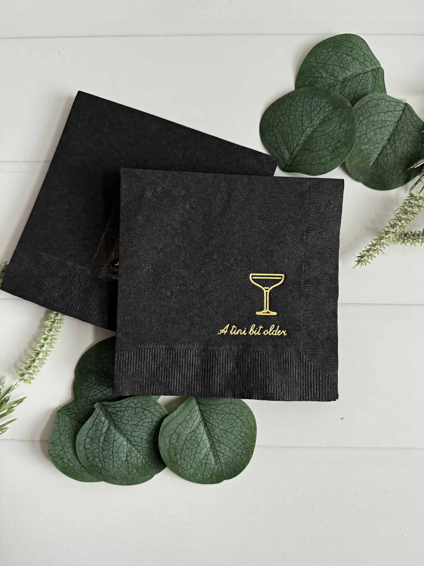 Our "A Tini Bit Older" birthday cocktail napkins, featuring sixteen exquisitely designed napkins in a sleek black color enhanced with captivating gold foil accents. Elevate your next birthday soirée or gathering
