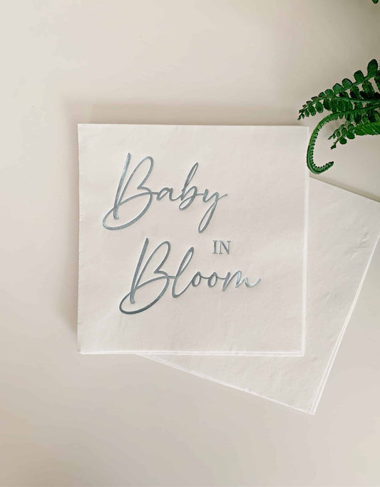 "Baby in Bloom" luncheon napkins in ice blue foil on white luncheon napkins - the perfect accent for your baby shower. A fun baby shower theme for spring and summer babies. These gorgeous baby blue foiled "Baby in Bloom" napkins are an EnFete original product. You won't find them anywhere else!