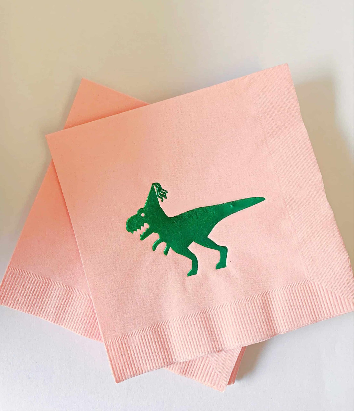 Add a pop of color to your girl's dinosaur-themed party with our Girl Dinosaur Birthday Napkins! These napkins come in a charming green and pink design, featuring a shiny green foil dinosaur on a pink background.