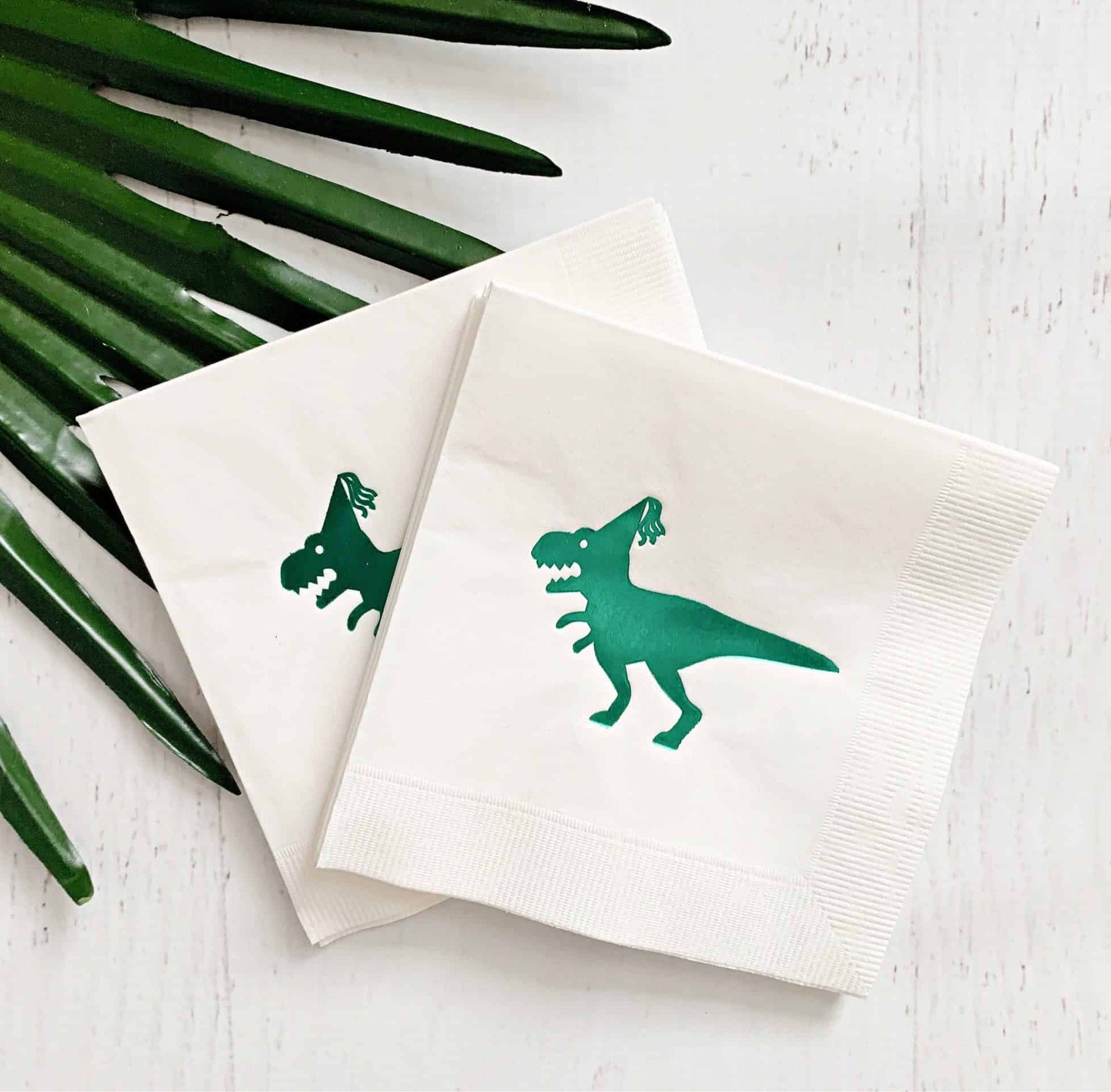 Introducing our EnFete original design green dinosaur drink napkins, perfect for your dinosaur-themed party! These napkins feature a beautiful shiny green foil dinosaur, adding a touch of whimsy to your celebration. The folded size of 4.5 x 4.5 inches makes them perfect for drinks or as kid-sized napkins.