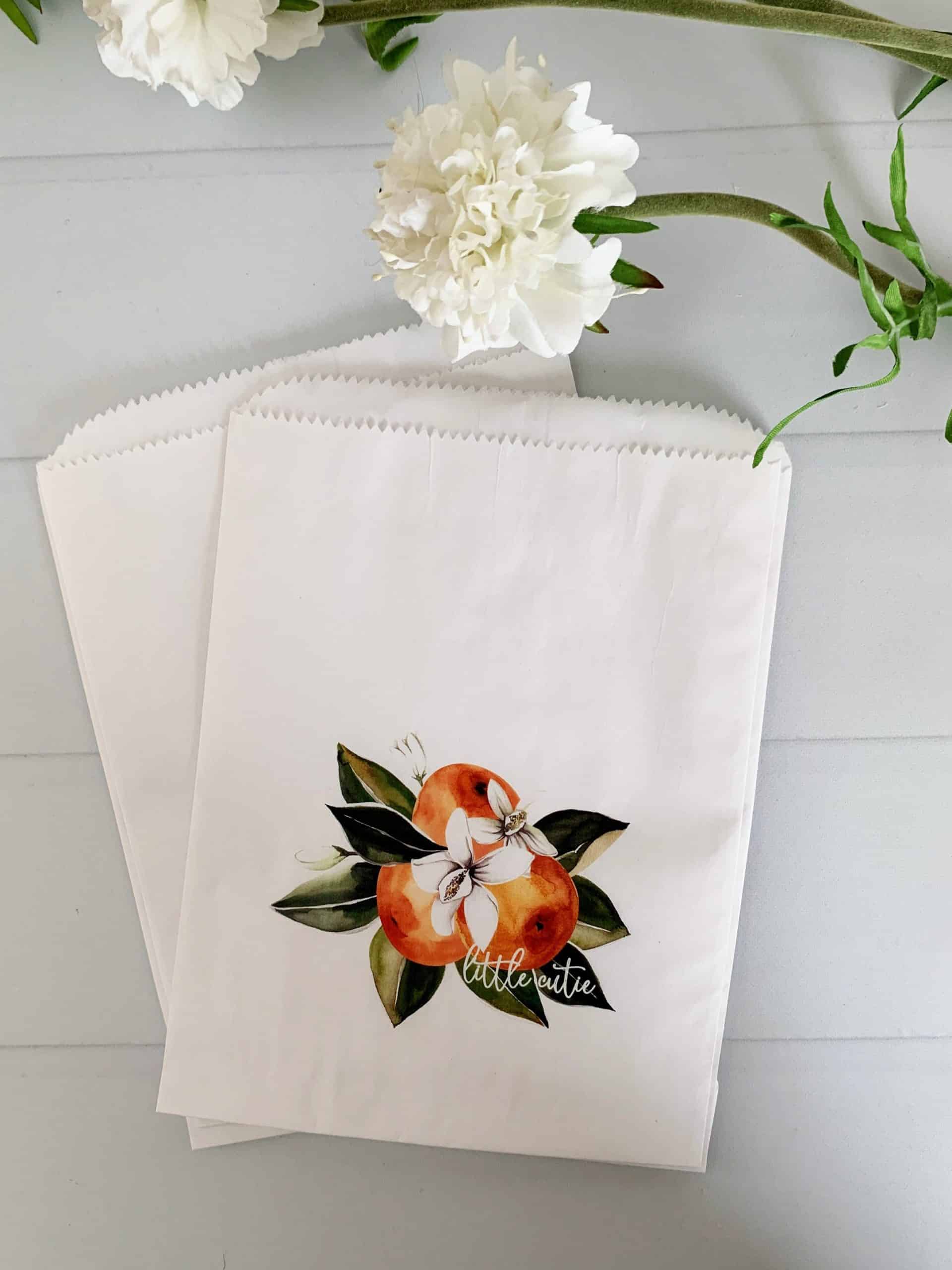 Image of 12 Little Cutie Citrus Treat Bags, each with a cluster of clementine cuties and "little cutie" on the fruit, perfect for a baby shower or candy bar display.