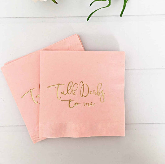 Elevate your Kentucky Derby party with EnFete's original and elegant Kentucky Derby napkins. Add sophistication to your celebration. #KentuckyDerby #ElegantNapkins #EnFete. These pink "Talk Derby to Me" cocktail napkins are perfect for Derby bridal showers or any festive event! The blush pink napkins feature a gold foil stamped "Talk Derby to Me" design, adding an elegant touch to any party decor.