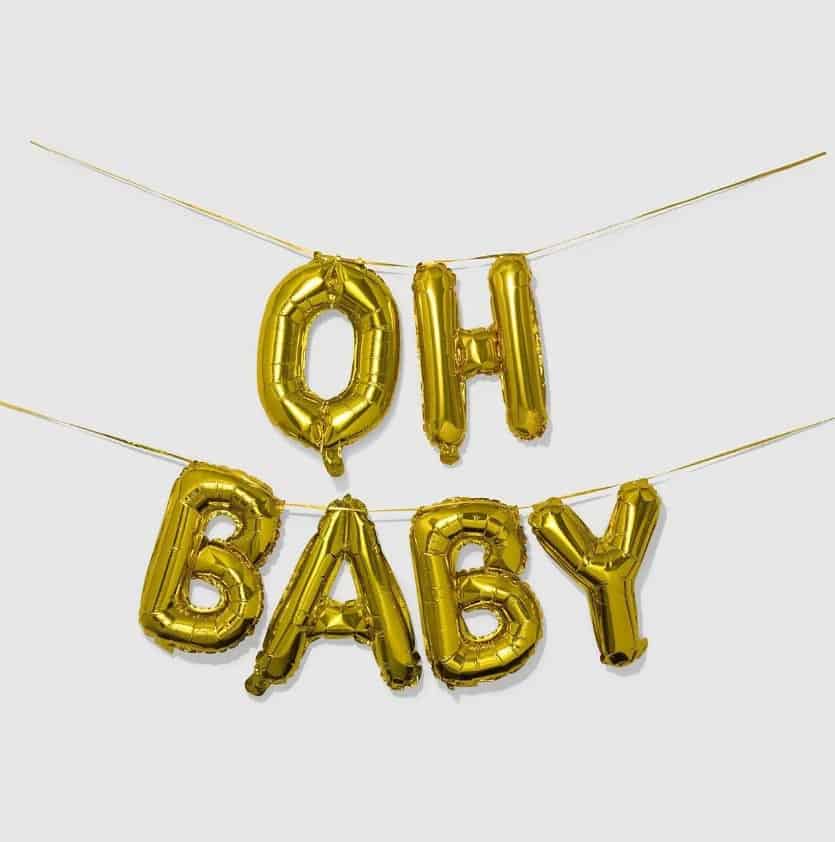 A beautifully styled photo of our "Oh Baby" gold foil balloon banner, fully inflated and spelling out the words in a playful and festive manner. The perfect addition to any baby shower, this banner will make a statement and bring joy to the occasion. #ohbaby #babyshower #goldfoil #balloons.