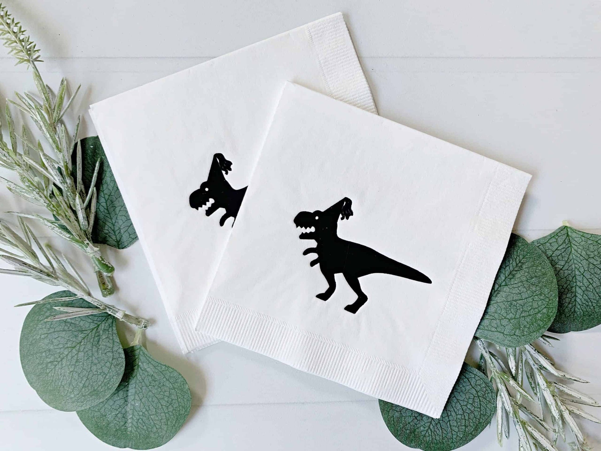 Celebrate your next dinosaur-themed party with these fun Black on White Dinosaur Drink Napkins from EnFete! These playful napkins are perfect for both adults and kids' birthdays, New Year's Eve, or any other special occasion that calls for a prehistoric touch. Featuring an EnFete original design of a dinosaur with a party hat, these napkins are sure to be a hit with your guests.