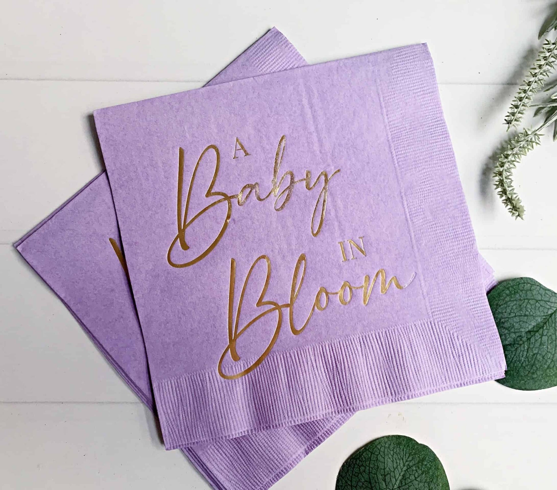 "A Baby in Bloom" in gold foil on lavender luncheon napkins - the perfect accent to your baby shower. These gorgeous gold foiled "A Baby in Bloom" napkins are an EnFete original product. You won't find them anywhere else!