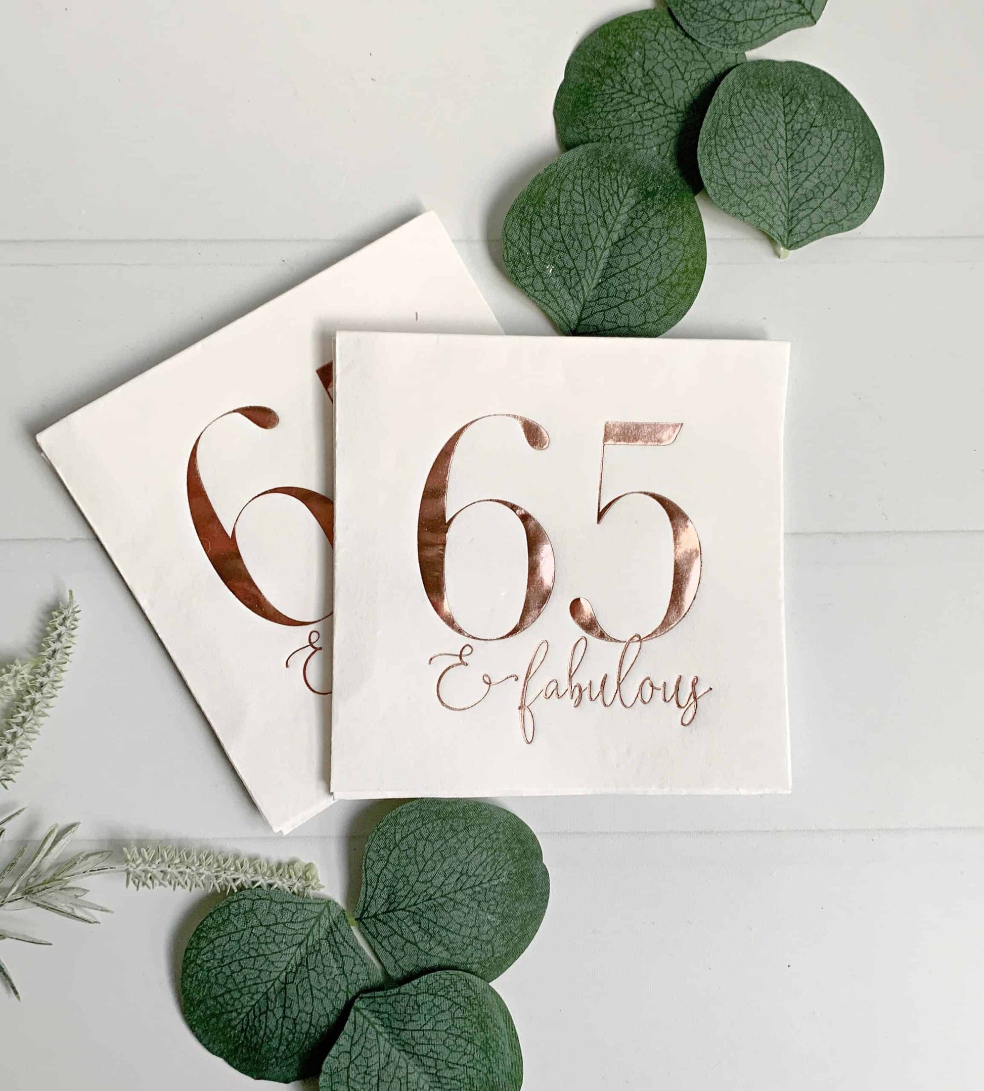 65 and fabulous rose gold cocktail napkins, perfect for a 65th birthday party, featuring a shiny metallic rose gold color and the message '65 and fabulous' in elegant font