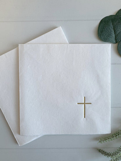White  luncheon sized napkin with gold cross design on a light gray surface