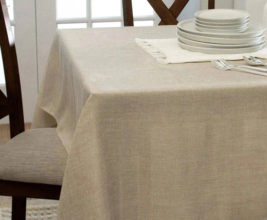 Beige tablecloth on a dining table with plates and cutlery in a bright room.