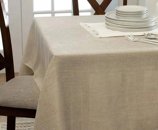 Beige tablecloth on a dining table with plates and cutlery in a bright room.