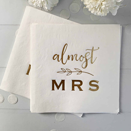 White luncheon napkins with 'almost Mrs.' text on a light gray background with white flowers.