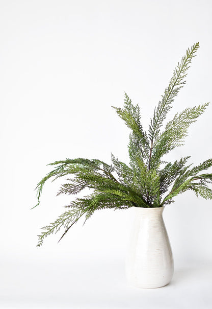Green pine bows that are very realistic a white vase on a white background