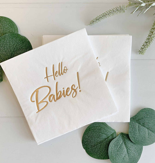 Introducing the stunning "Hello Babies Cocktail Napkins - Gold," designed to add an air of elegance to any occasion. The captivating gold foiled scripted writing that adorns these napkins is sure to catch the eye and leave a lasting impression. Against a backdrop of neutral white, these napkins effortlessly exude sophistication. The perfect napkins for a baby shower for twins or multiples.