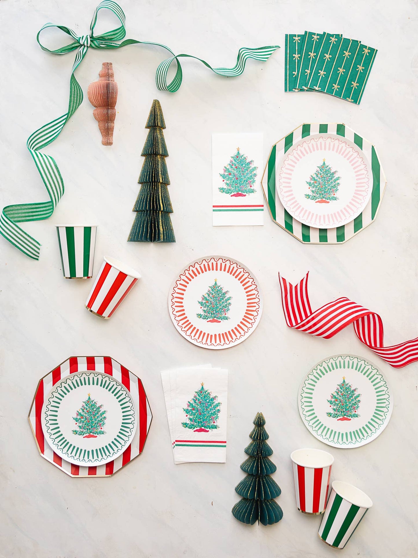 Christmas-themed tableware including plates, cups, and napkins with tree designs on a white background.