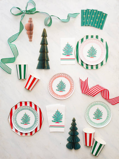 Christmas-themed tableware including plates, cups, and napkins with tree designs on a white background.