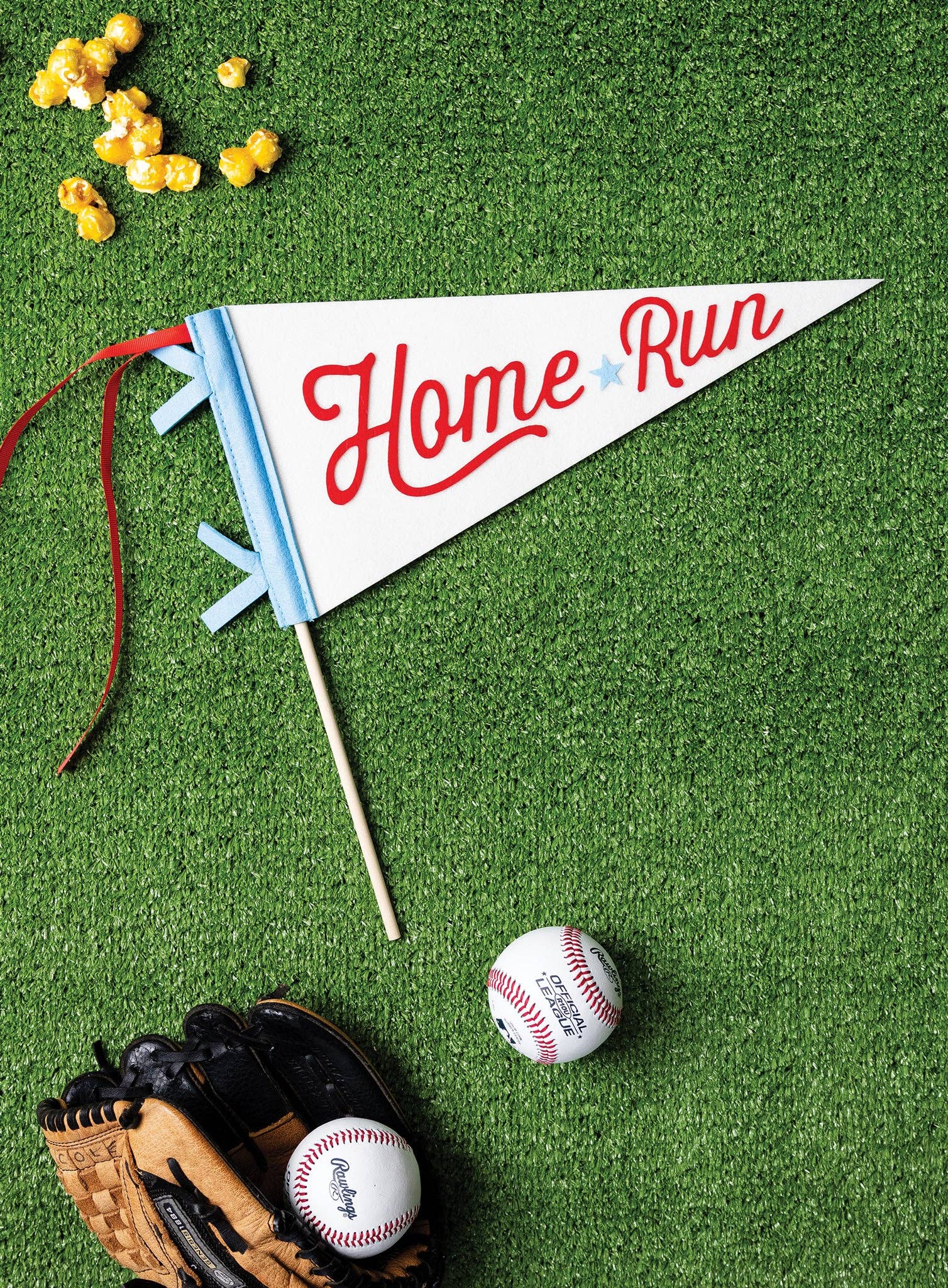 Baseball-themed decor with 'Home Run' pennant, baseballs, and a glove on green grass.
