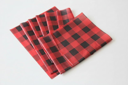 Four folded sheets of tissue paper with a red and black buffalo plaid pattern, arranged in a fan shape on a plain white background.