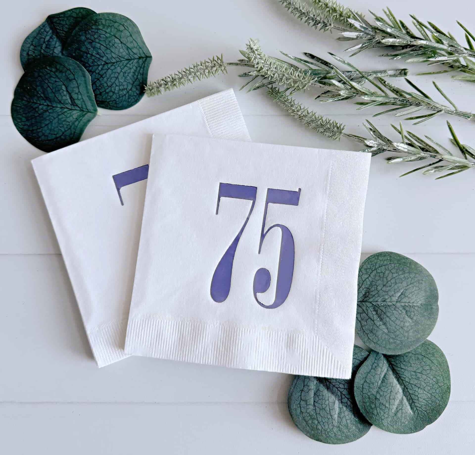 Introducing our eye-catching cocktail napkins featuring a bold retro lavender foil number 75 on a crisp white background. This design beautifully merges modern aesthetics with a touch of nostalgia, making it an ideal choice for celebrating a 75th birthday.