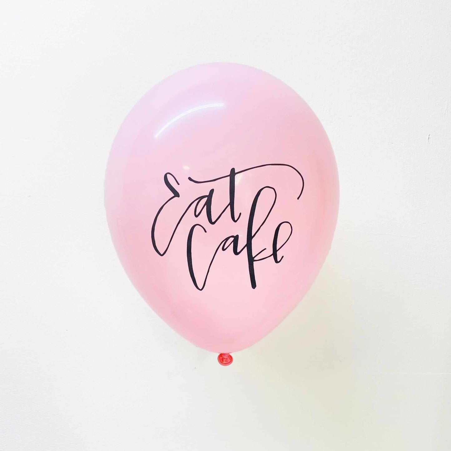 Soft pink balloons with black calligraphy Eat Cake lettering on the front