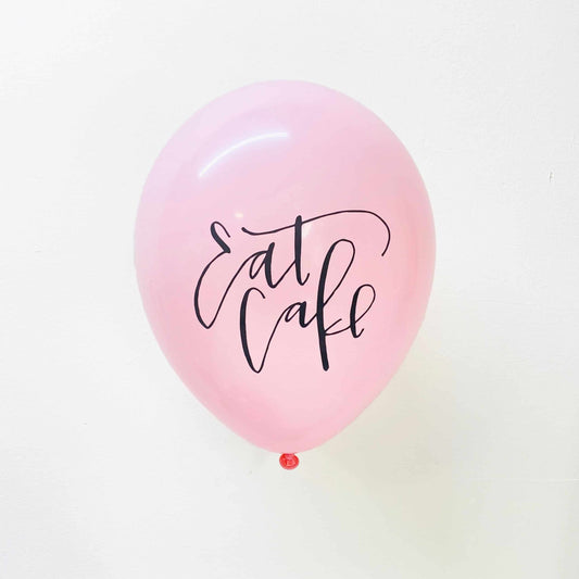 Soft pink balloons with black calligraphy Eat Cake lettering on the front