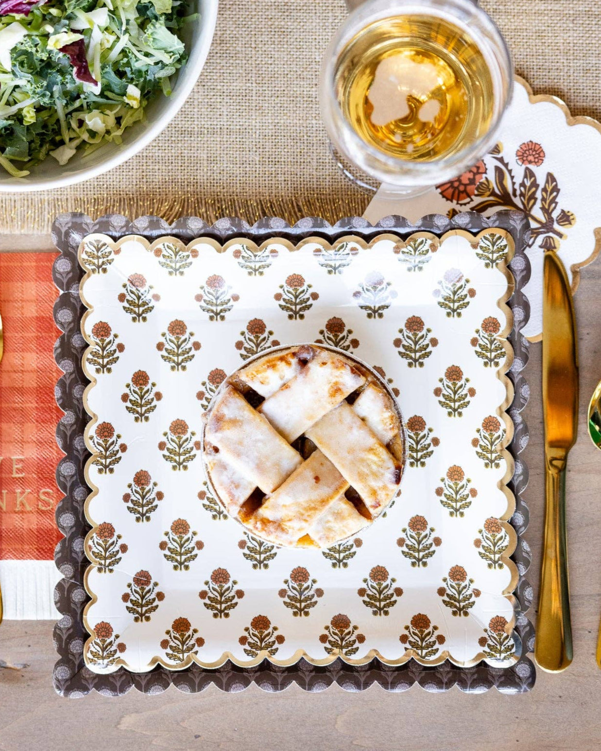 Thanksgiving table setting with salad, pie, and autumn-themed placemat.