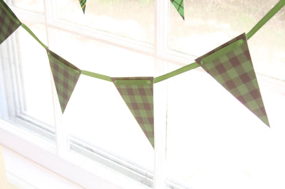 Green and black buffalo check plaid bunting banner garland hanging in front of a bright window.