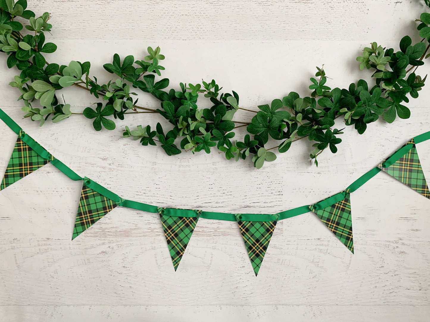 Green shamrock garland and Scotch plaid bunting banner on a white wood background for party decor for Christmas