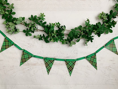 Green shamrock garland and Scotch plaid bunting banner on a white wood background for party decor for Christmas