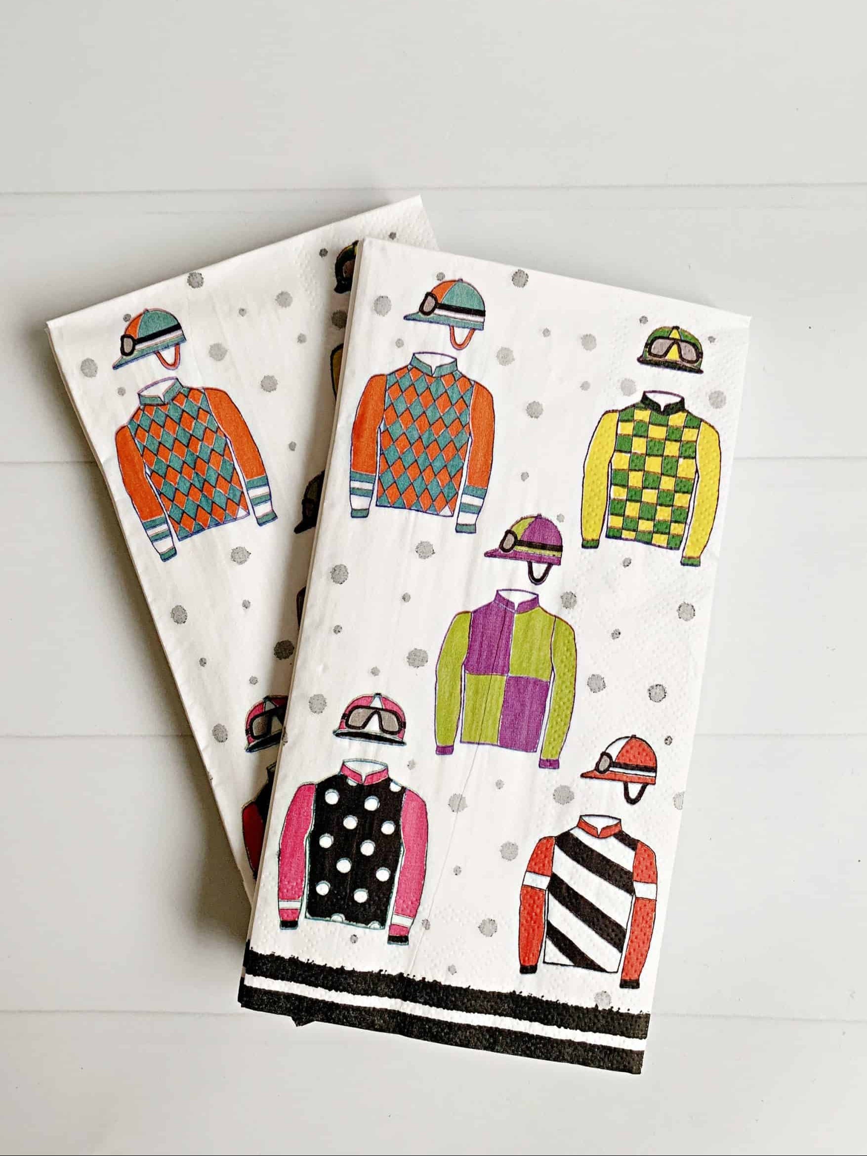 Two folded towels with colorful jockey silks design on a white background