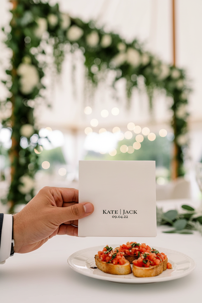 Man's hand holding personalized wedding napkin with appetizer
