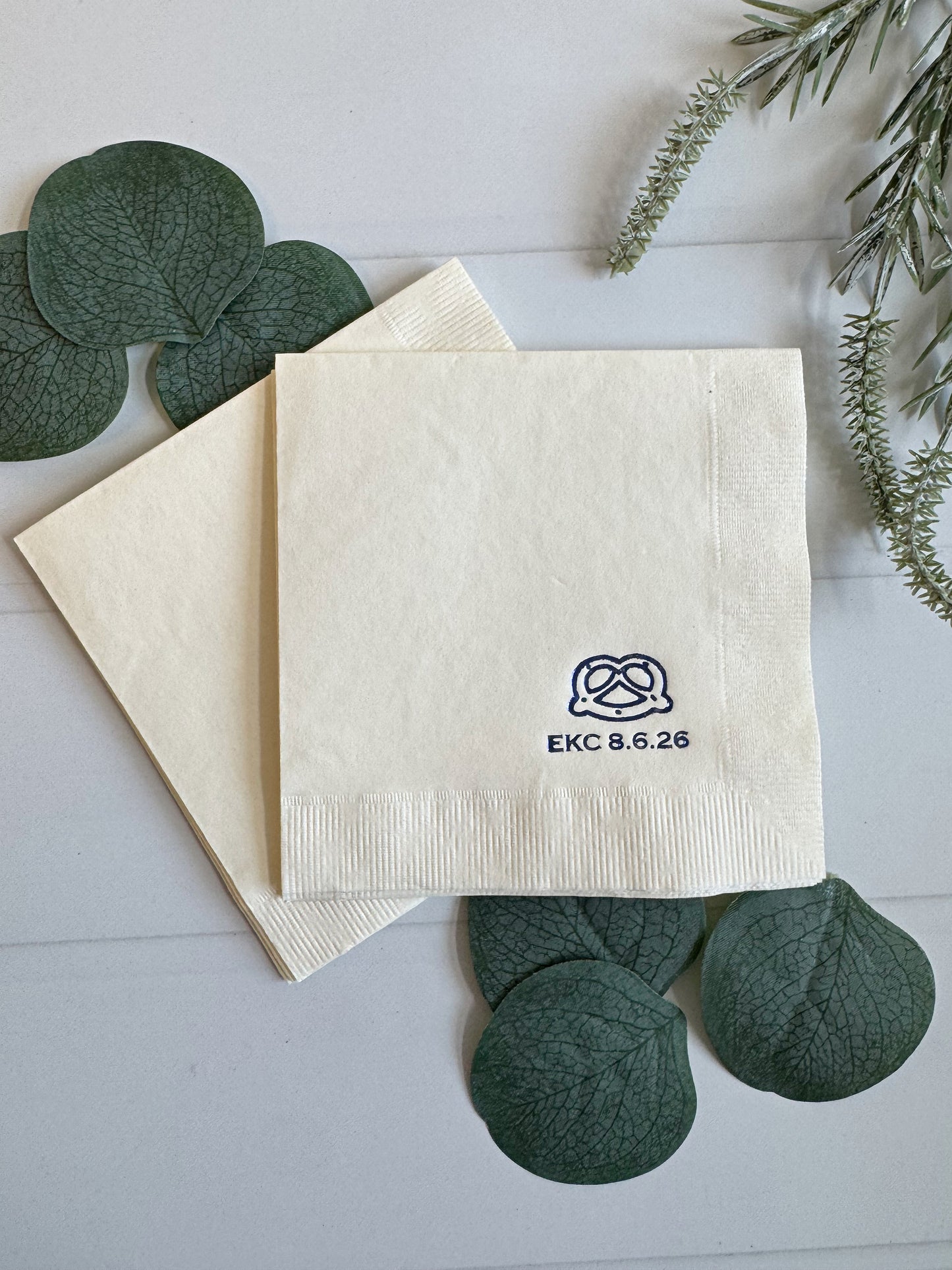 Personalized pretzel icon napkins for oktoberfest, beer tasting, circus parties, or just for entertaining at home this fall.  Blue foil embossed pretzel and initials on a cream designer three ply napkin. Made in the USA by EnFete.
